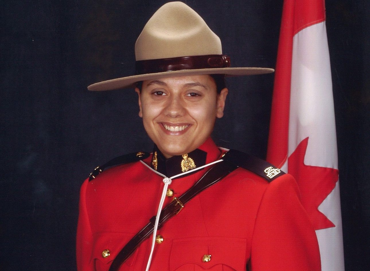 Constable Sarah Beckett is pictured in her full RCMP uniform in front of a Canadian flag
