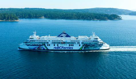 A BC Ferries vessel in the water, with land in the background