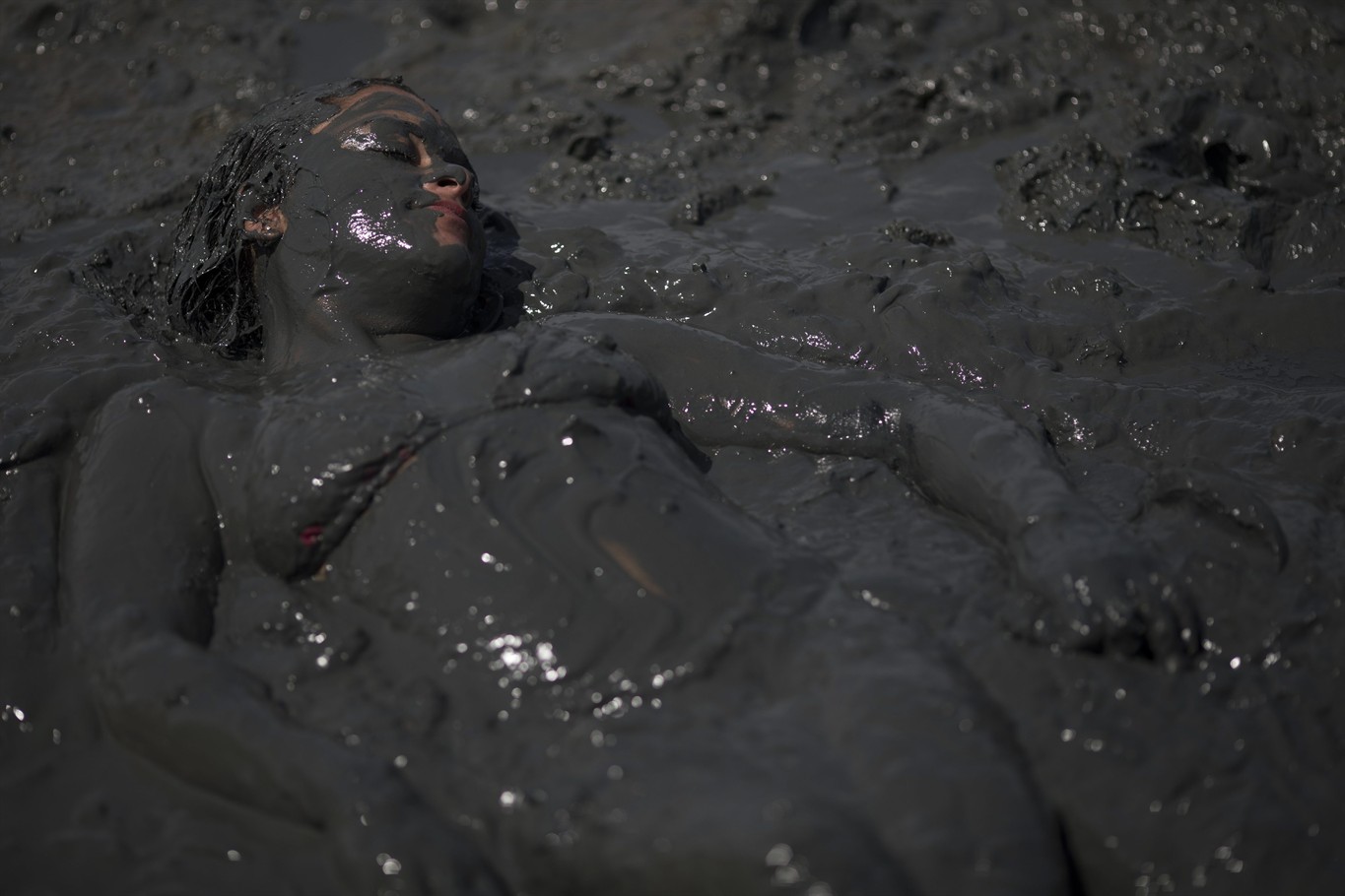 10, 2018 photo, a mud covered woman lays in the mud during the traditional ...