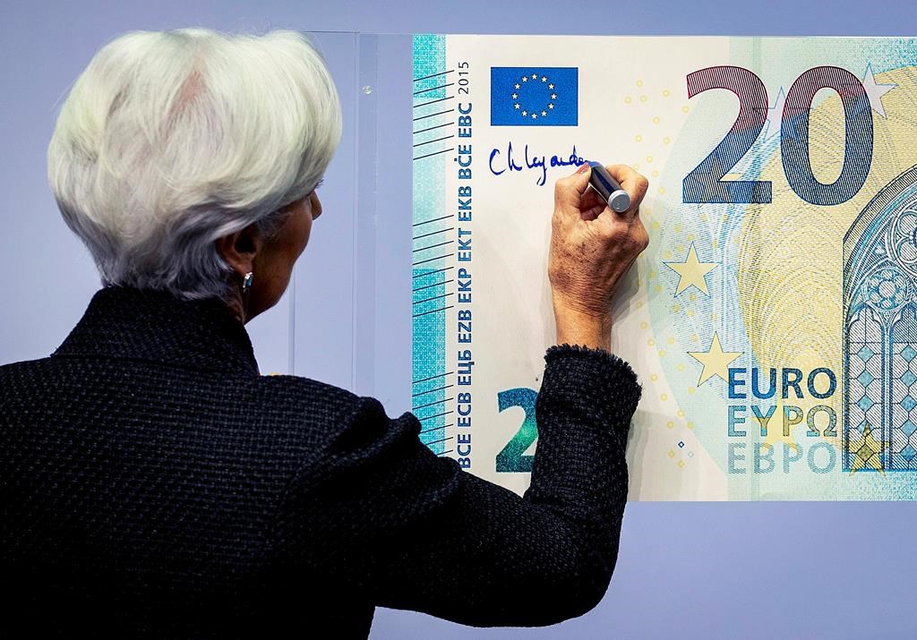 The new President of the European Central Bank Christine Lagarde adds her signature to an oversize euro banknote at the ECB in Frankfurt, Germany, Wednesday, Nov. 27, 2019. (AP Photo/Michael Probst)