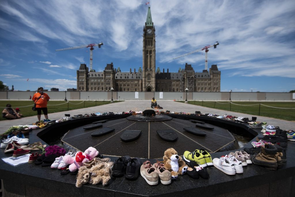 Shoes line the edge of the Centennial Flame on Parliament Hill in memory of the 215 children whose remains were found at the grounds of the former Kamloops Indian Residential School at Tk’emlups te Secwépemc First Nation in Kamloops, B.C., on May 30, 2021, THE CANADIAN PRESS/Justin Tang