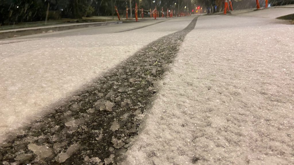 Tire tracks are seen up close on a snow-covered street