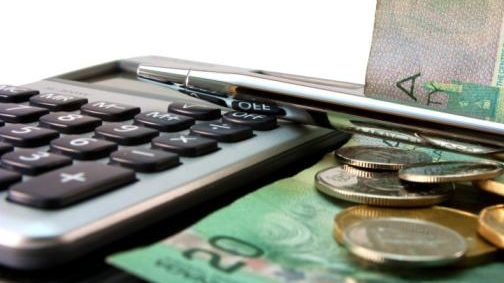 A calculator and Canadian money sits on a desk