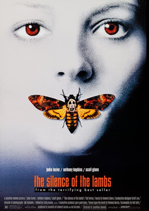 A movie poster shows the face of a pale white face with red eyes and an orange moth covering the mouth