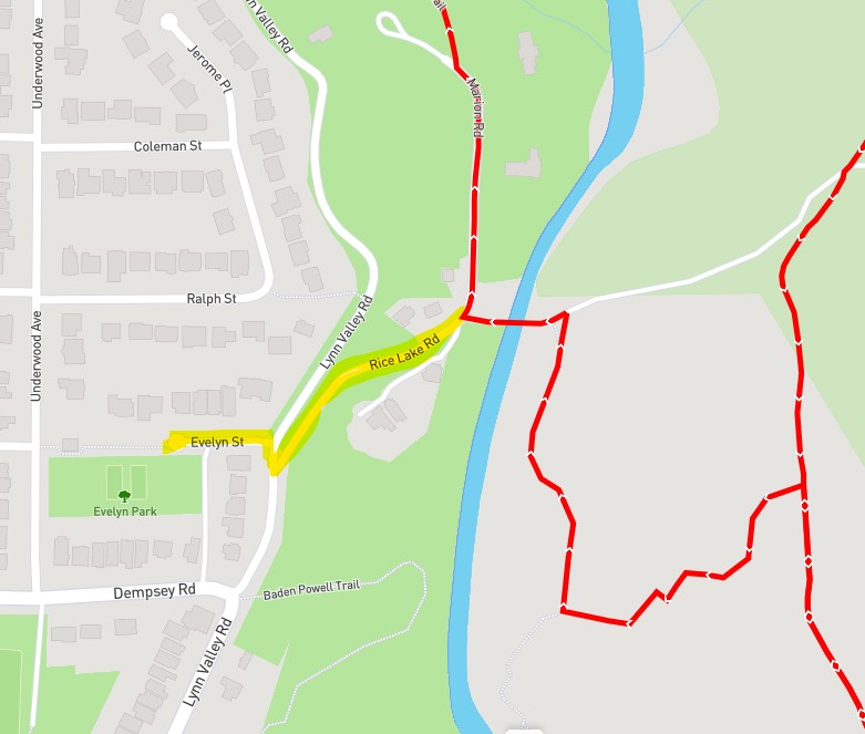 A map of a specific area in North Vancouver coloured light grey and green shows a location highlighted in yellow, with another red line crossing the right side of the frame mostly vertically