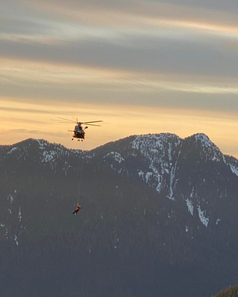 A photo of a talon helicopter from North Shore Rescue performing a long line rescue of an injured hiker