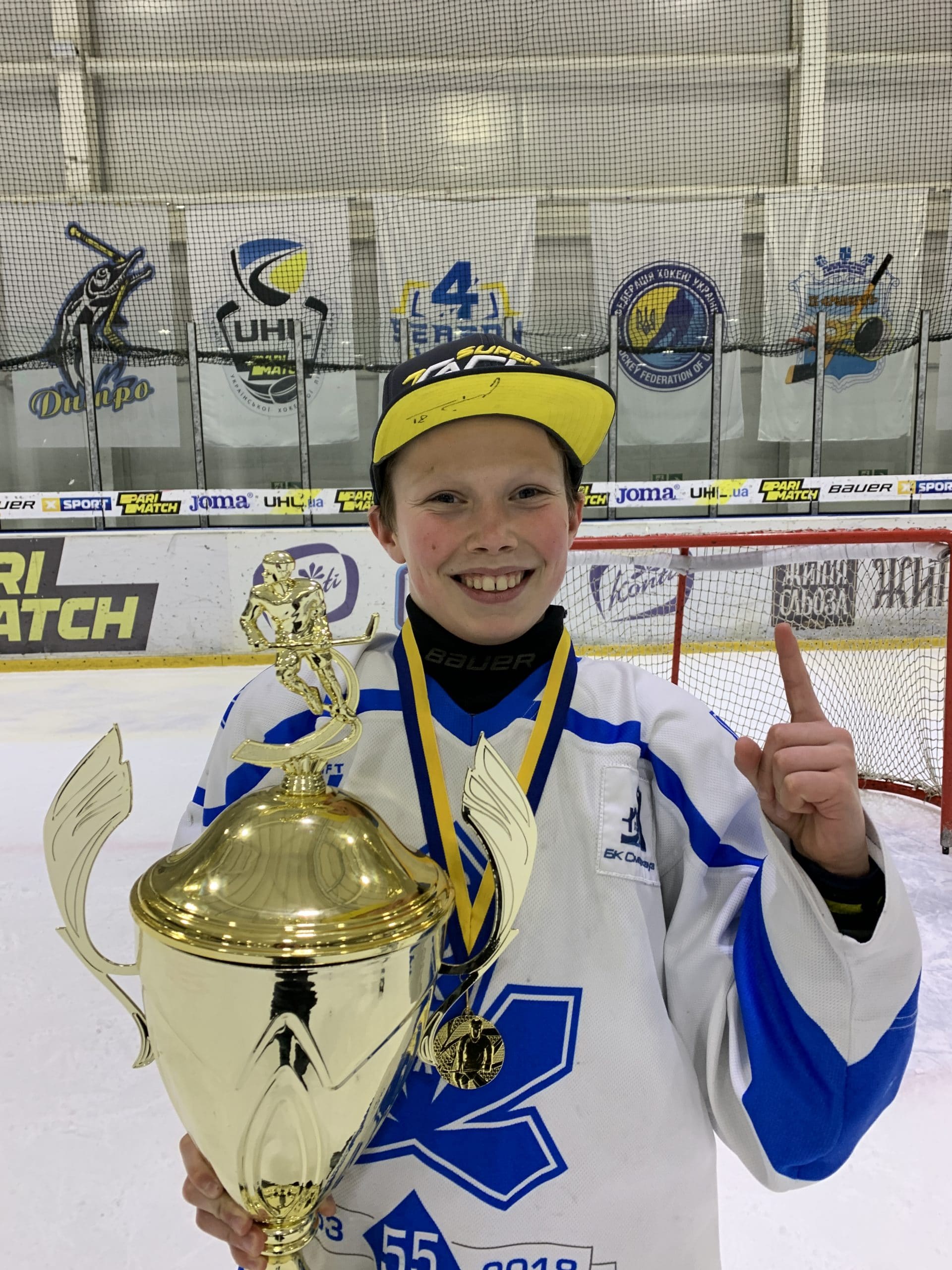 Ukrainian teen Dany Bereza with a hockey trophy holding up a hand gesturing number 1
