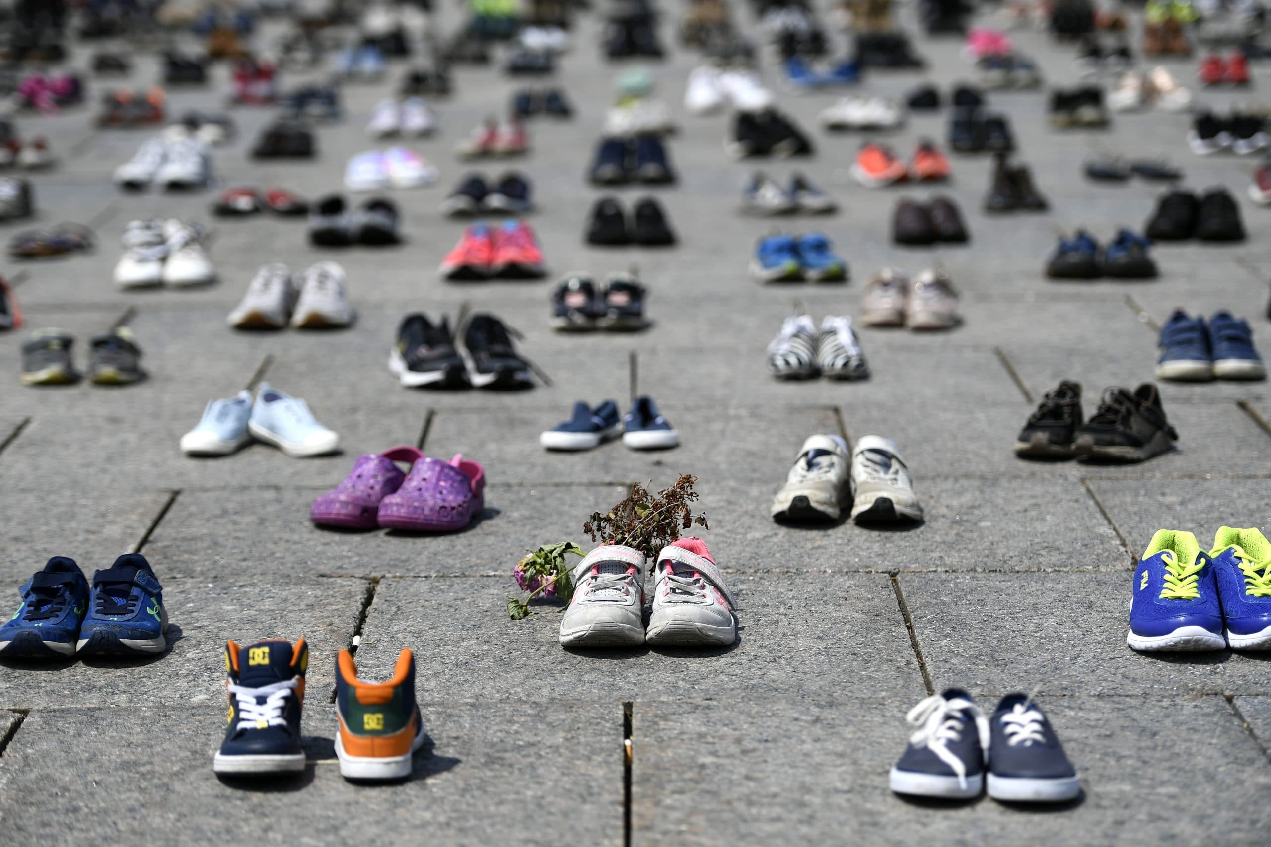 Children's shoes are lined up on the ground on Parliament Hill in Ottawa