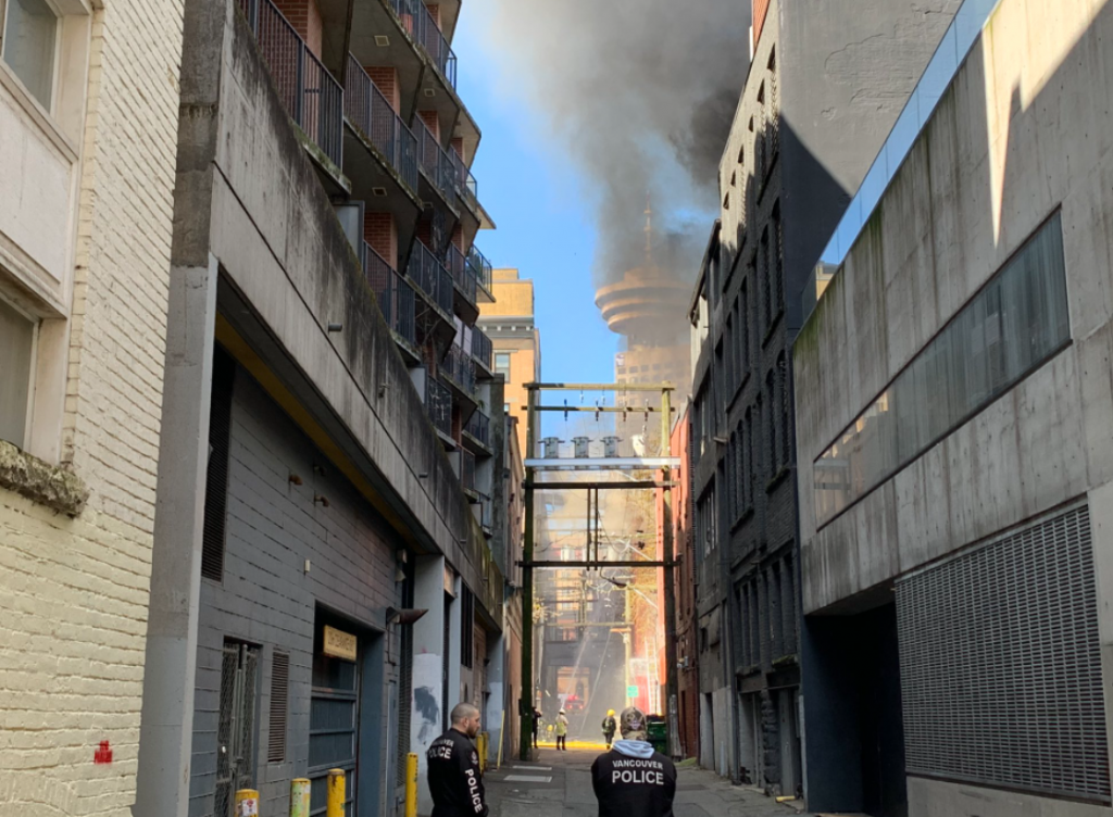 Smoke is seen rising from a building in Vancouver's Gastown neighbourhood as crews battle the blaze from an alley