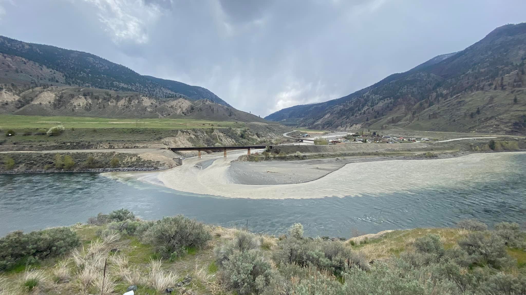 The Nicola River, a bridge, and two mountains in the background