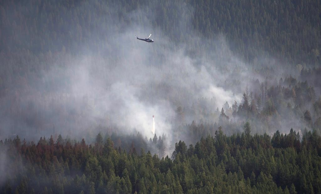 A helicopter dumps water on a fire outside Kelowna, B.C.,