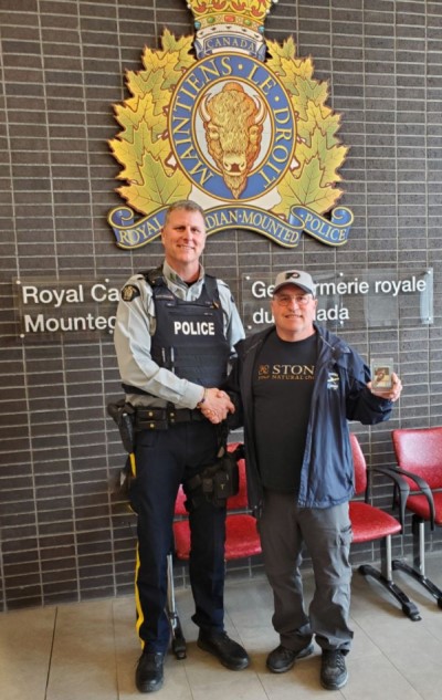 An RCMP officer shakes a man's hand after a valuable Wayne Gretzky hockey card was returned to him years after it was stolen