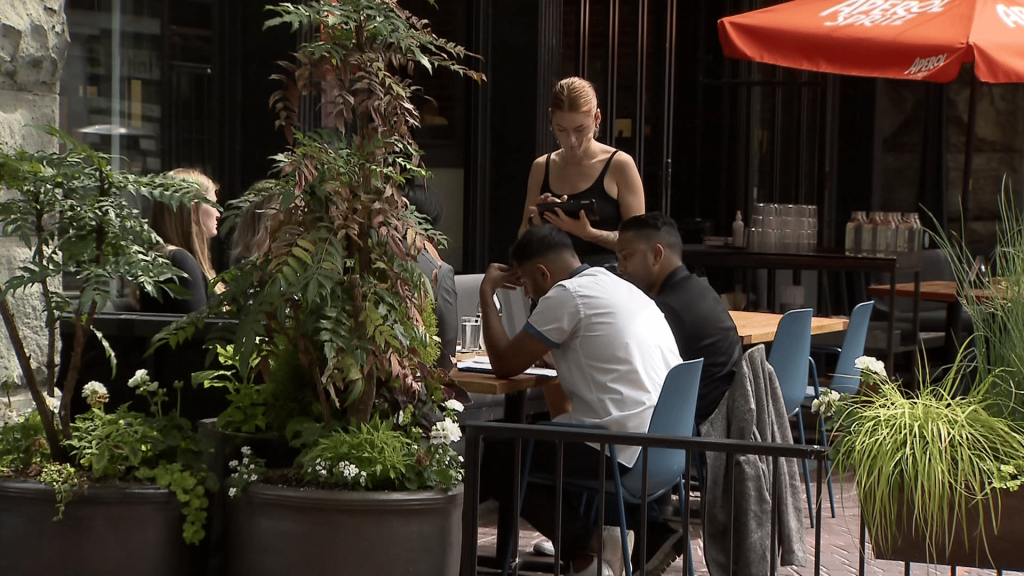A server stands at a table with patrons seated