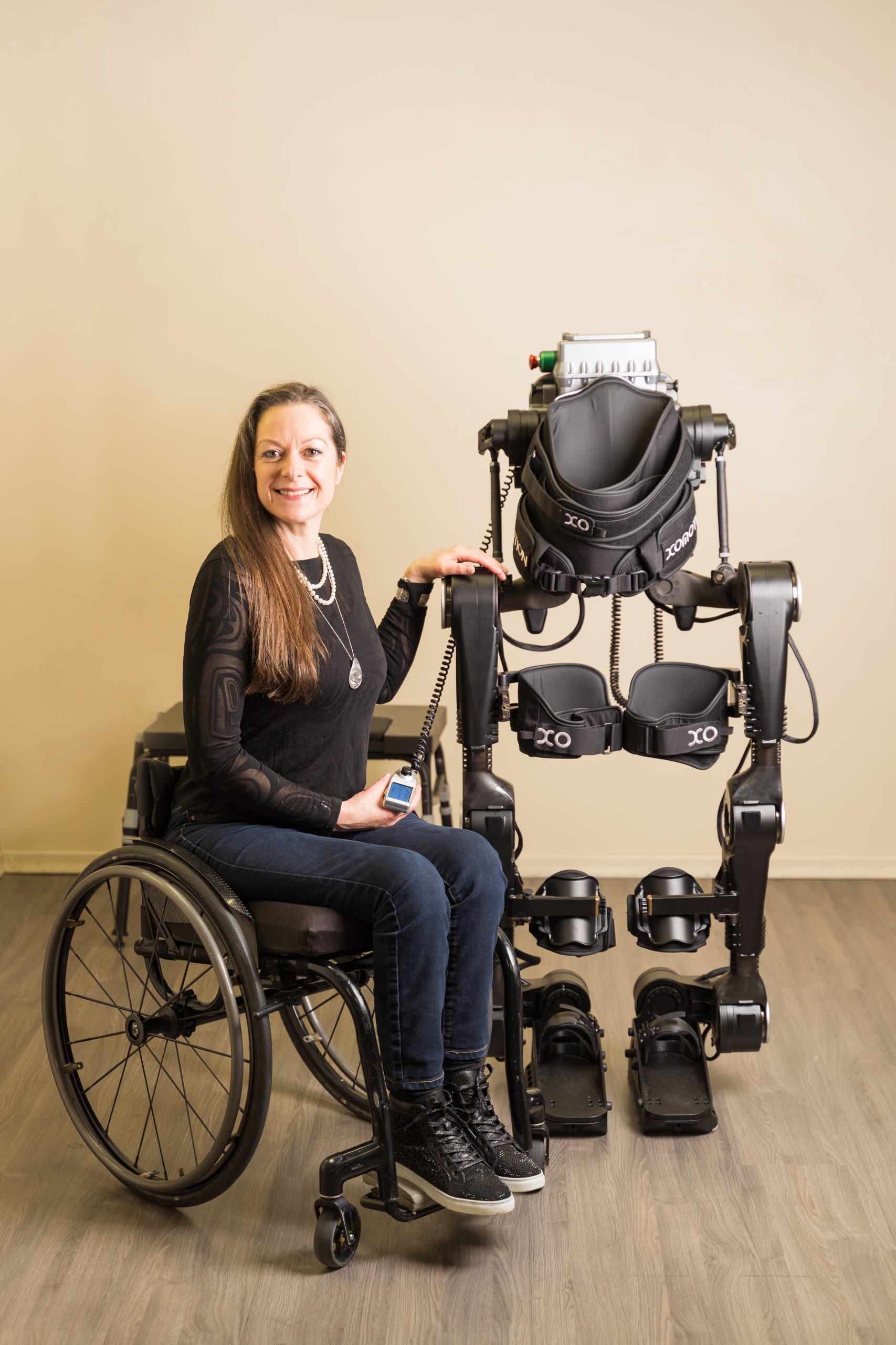 Chloe Angus sits in her wheelchair next to a wearable exoskeleton