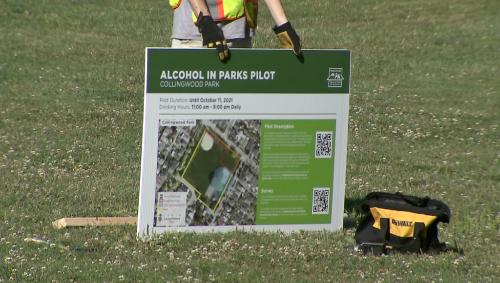 A Vancouver city worker holds up a sign outlining rules for its alcohol in parks pilot project
