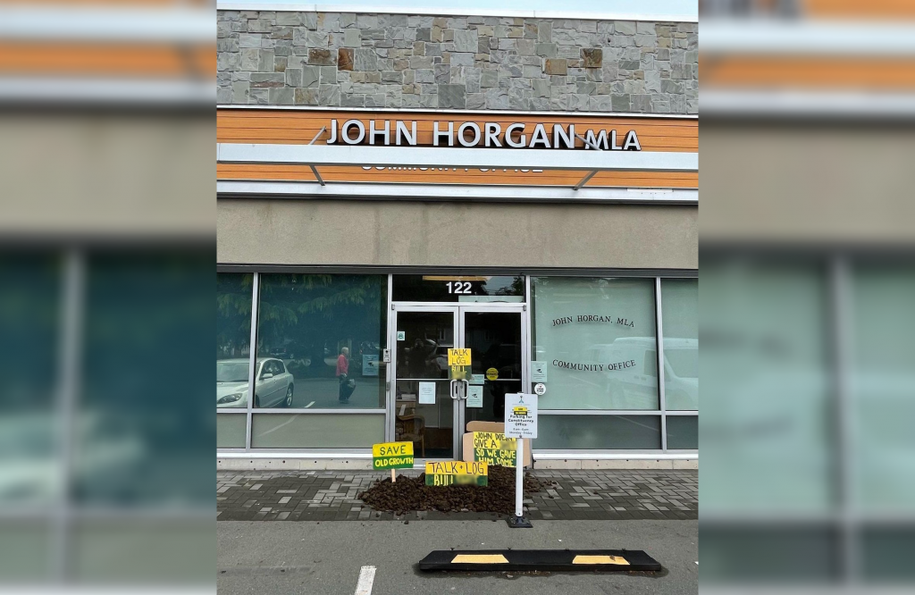 A pile of manure with various signs targeting John Horgan sits outside of the premier's constituency office