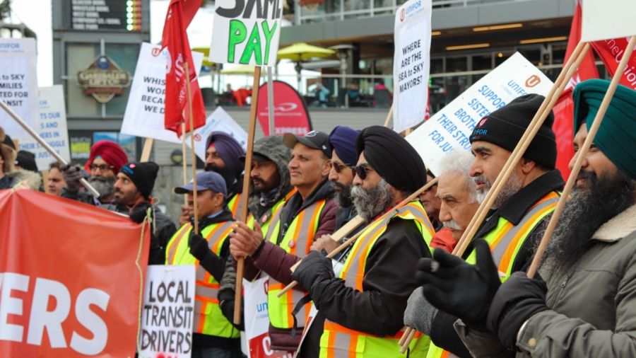 A picket line with transit workers wearing high-viz vests and holding signs