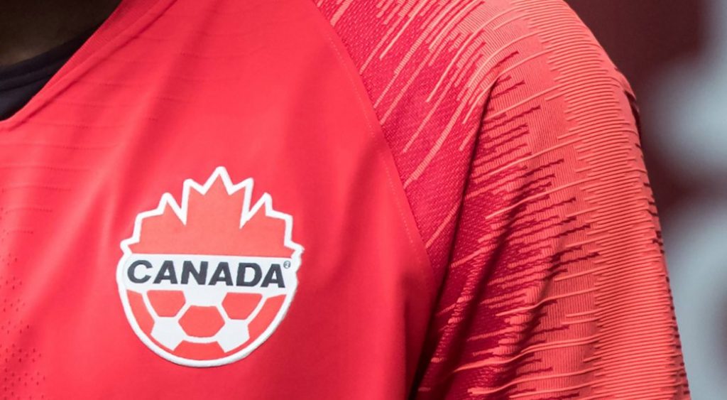 A Canada soccer logo is seen on a player's chest