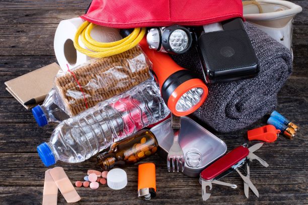 A photo of a emergency kit which has a water bottle, flashlight, knife, food, and medication in case of an evacuation. 