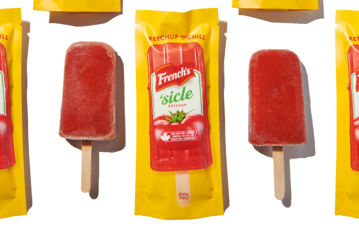 Red-coloured popsicles are seen next to packaging with a ketchup popsicle ad on it