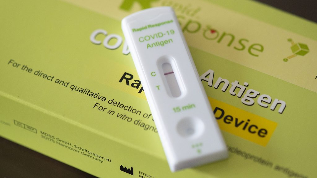 A COVID-19 rapid test shows a negative result as it lays on yellow packaging