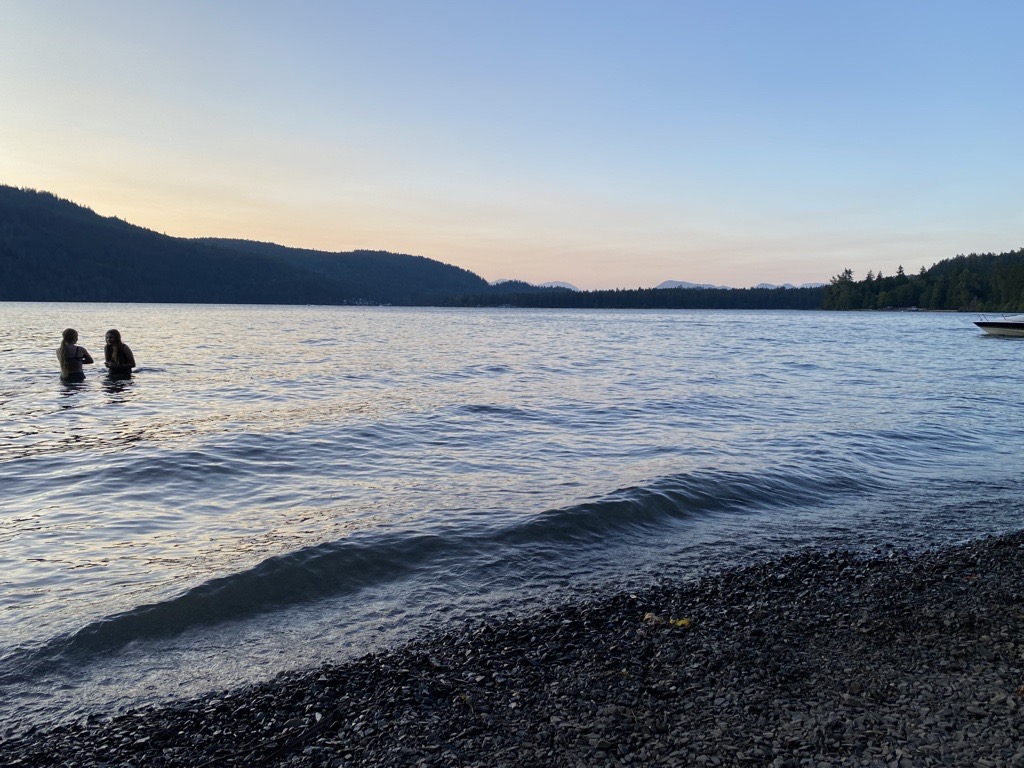 A photo of two people wading in Cultus Lake, B.C. during a sunset in 2022.