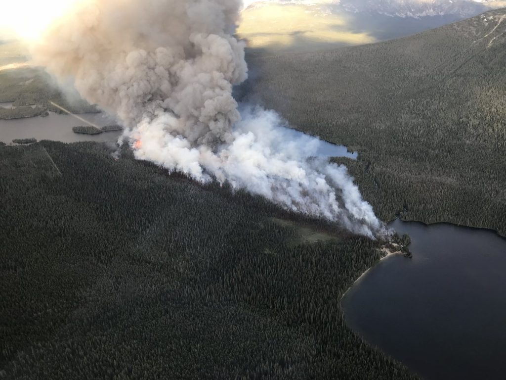 Smoke from a wildfire rises from a forested, mountainous area of B.C.'s Cariboo region