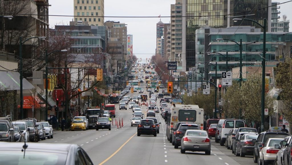 Cars drive down Broadway in Vancouver, with buildings lining either side of the road