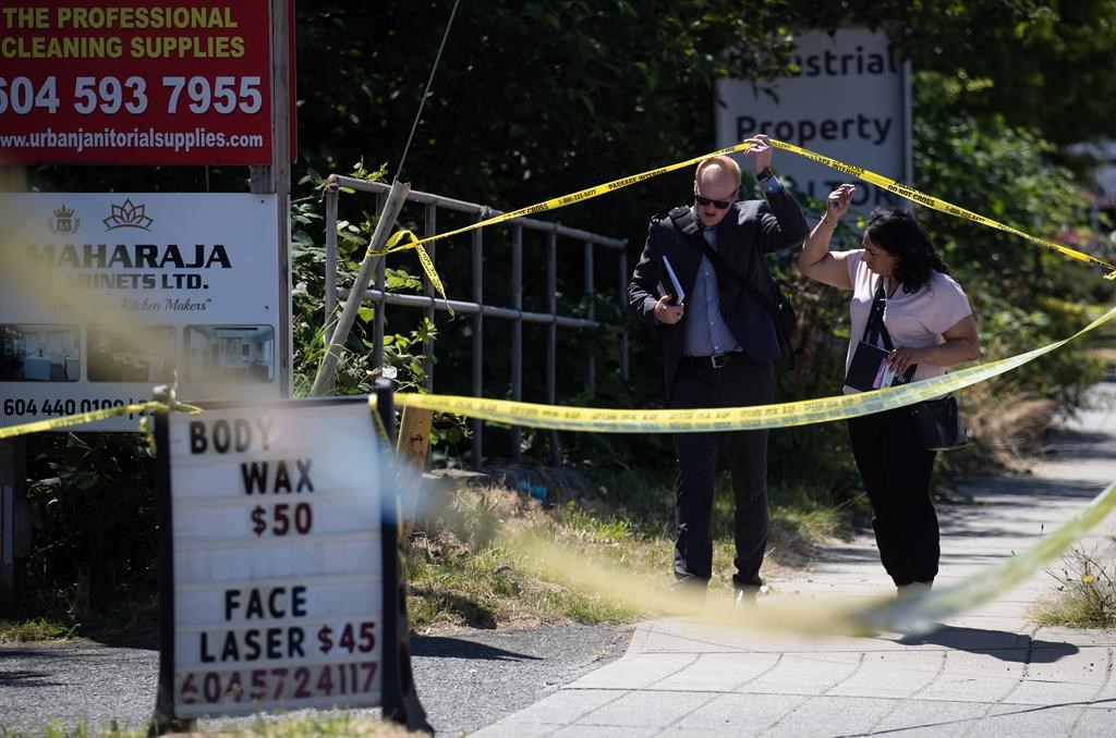 Investigators cross police tape blocking a section of the street