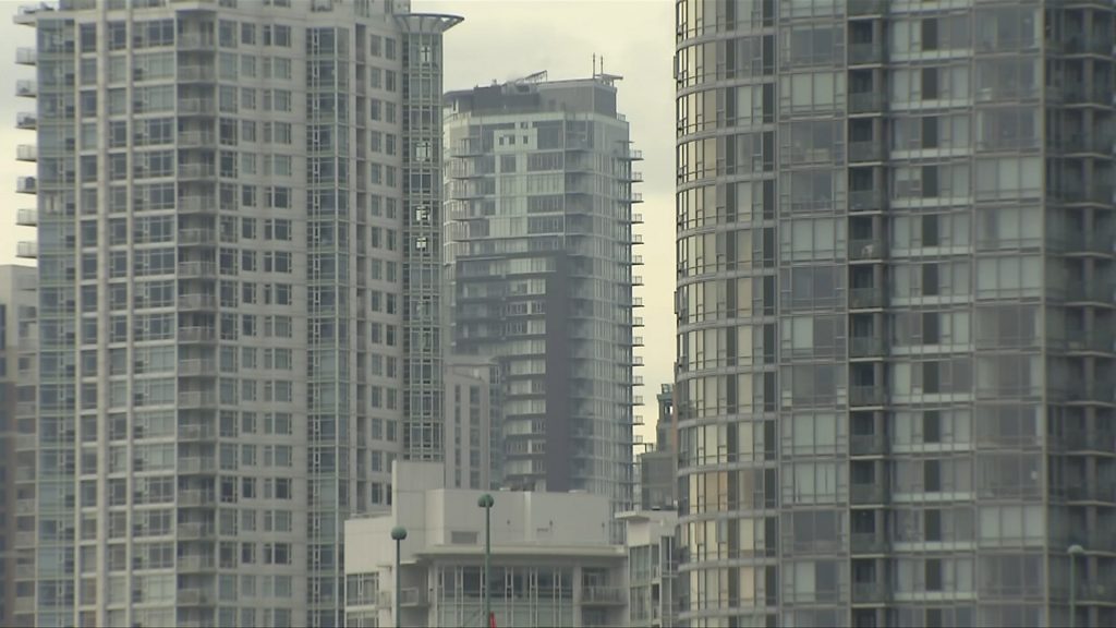 Three tall residential buildings lined with windows stand against a cloudy sky backdrop