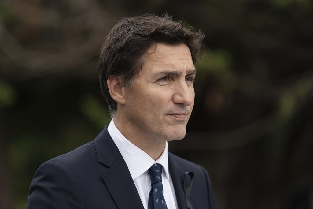 Prime Minister Justin Trudeau looks on while wearing a dark suit, white shirt, and dark tie