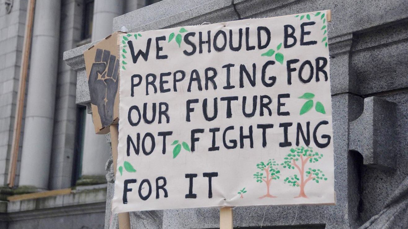 A sign that reads 'We should be preparing for our future not fighting for it' propped up against a cement building