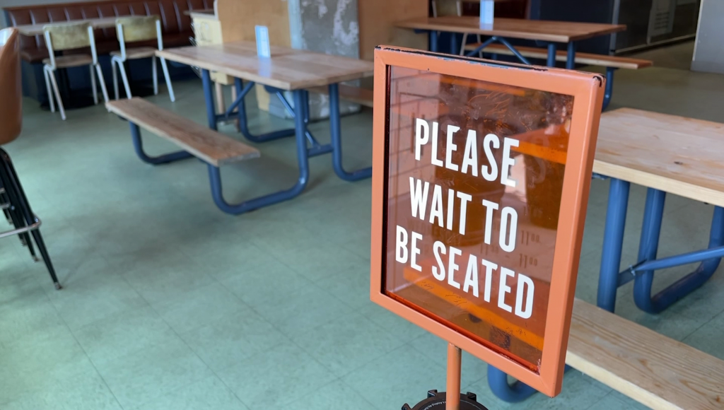 A 'Please wait to be seated' sign at a restaurant