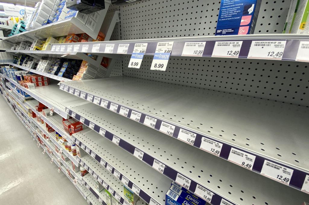 Nearly empty shelves with just a few boxes of medication are pictured in a store., price tags in front of empty spots show the lack of stock.