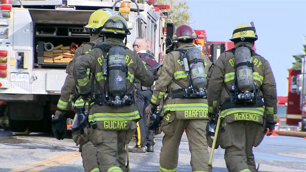 Four Burnaby firefighters walk toward a fire truck during a call in the Capitol Hill neighbourhood