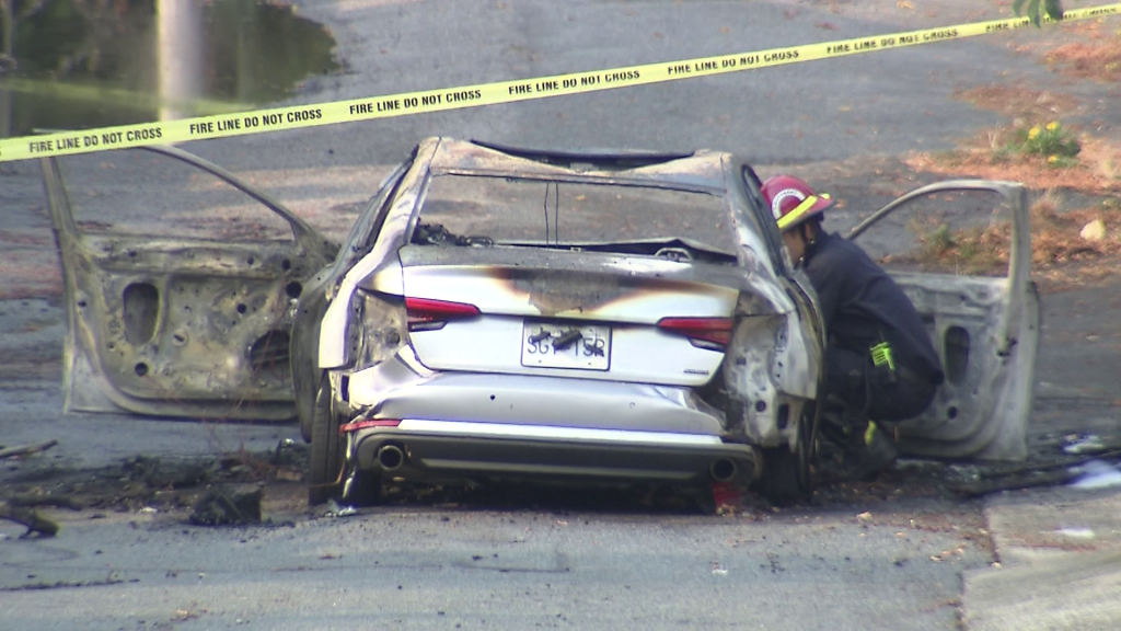 A burnt out car sits in a Vancouver alleyway