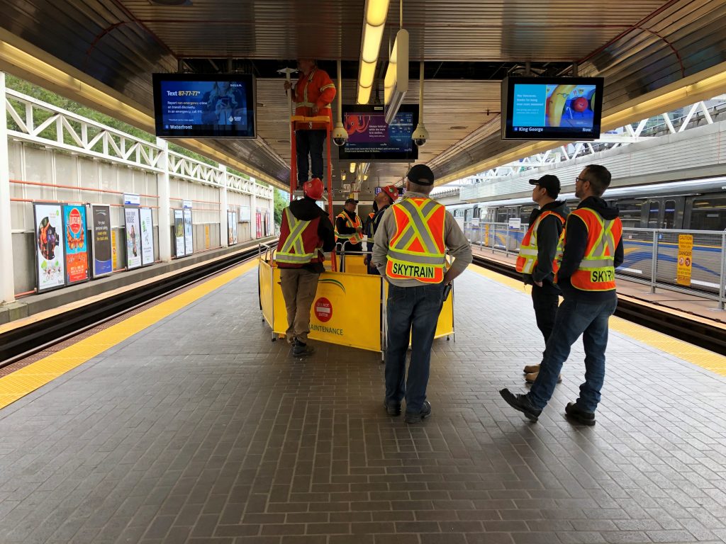 Stadium SkyTrain platform in Vancouver with workers standing