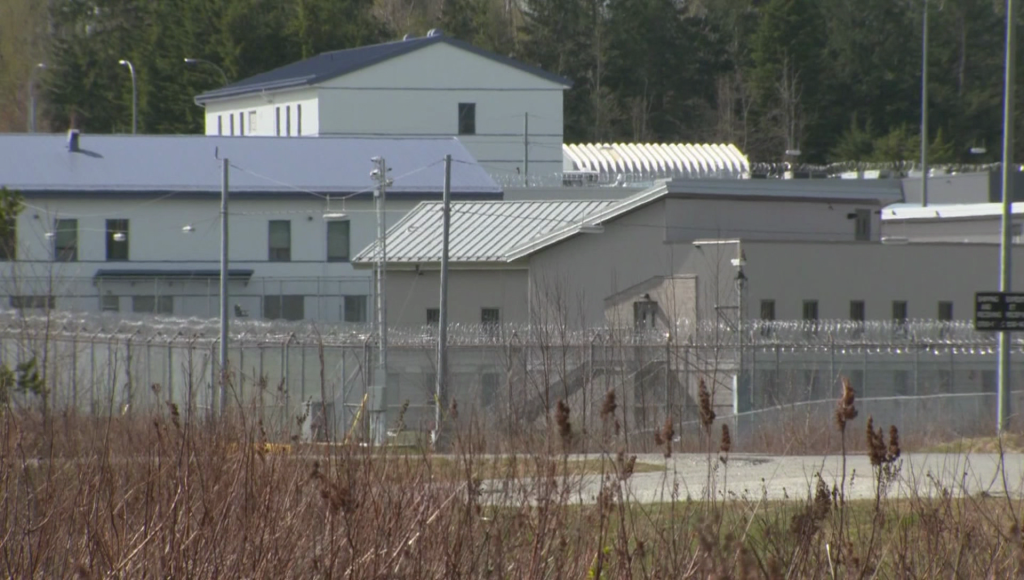outside of prison, grey and white buildings surrounded by barbed wire