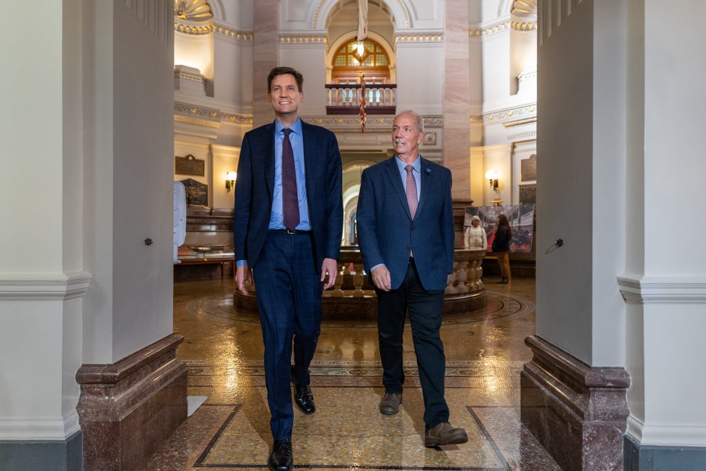 John Horgan and David Eby walk down a hall