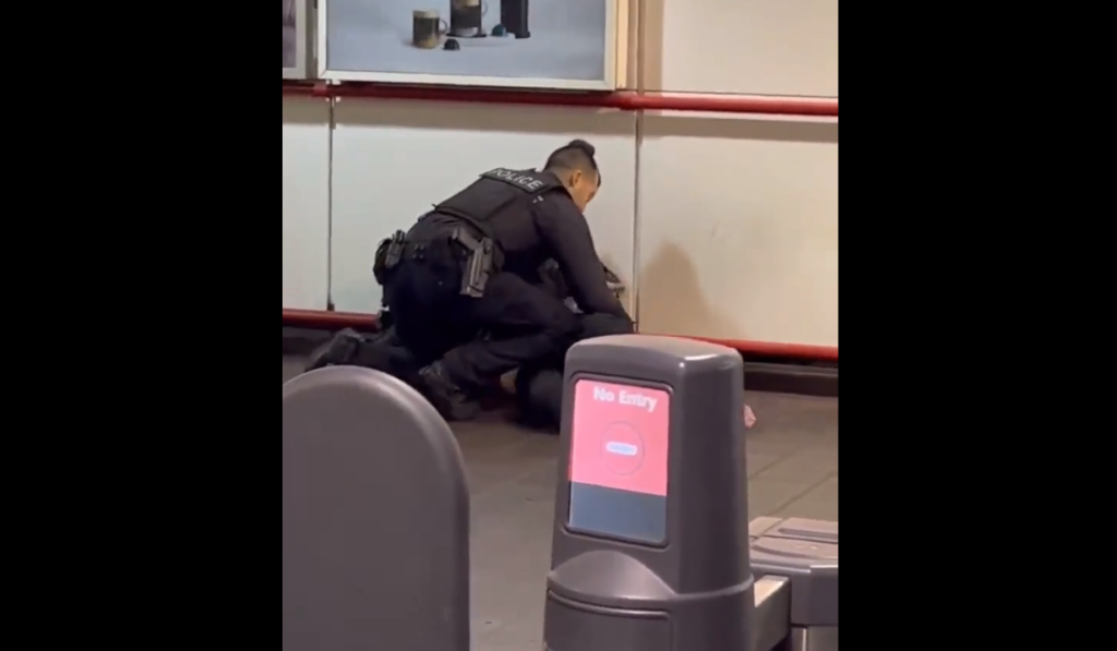 A screenshot of a video showing two Transit Police officers arresting a woman at a Vancouver SkyTrain station