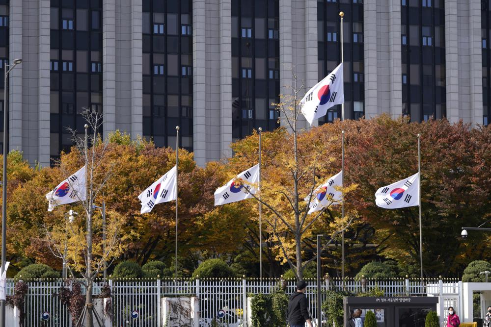South Korean national flags fly at half-mast at the government complex in Seoul, South Korea, Sunday, Oct. 30, 2022. A mass of mostly young people celebrating Halloween festivities in Seoul became trapped and crushed as the crowd surged into a narrow alley, killing dozens of people and injuring dozens of others in South Korea's worst disaster in years.