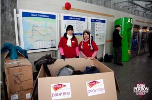 two women stand in front of cardboard box full of blanket donations