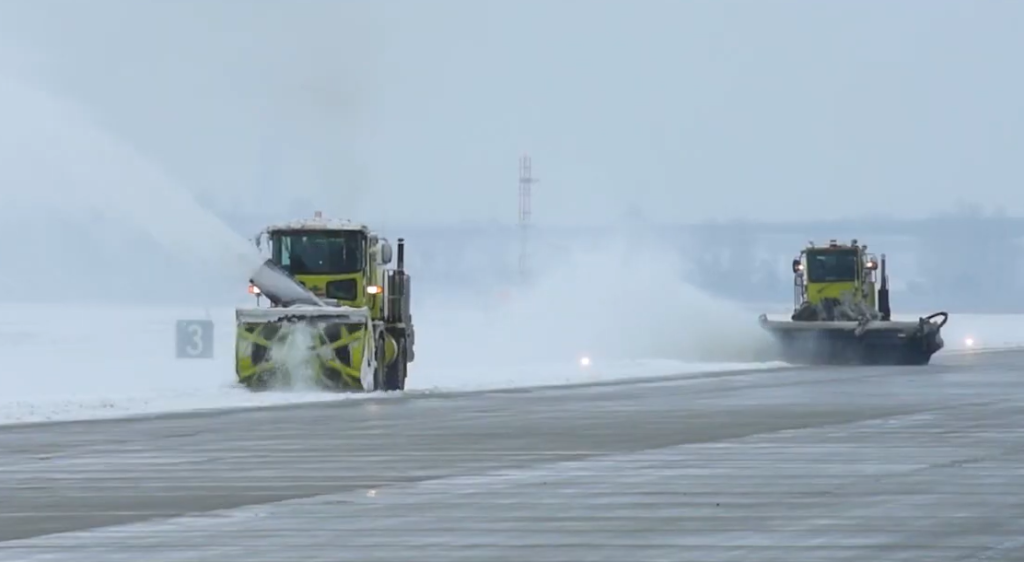 Two plows on a YVR runway clear snow during a winter storm
