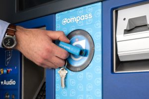 A blue Compass Mini-Train is pictured tapping a TransLink fair machine.