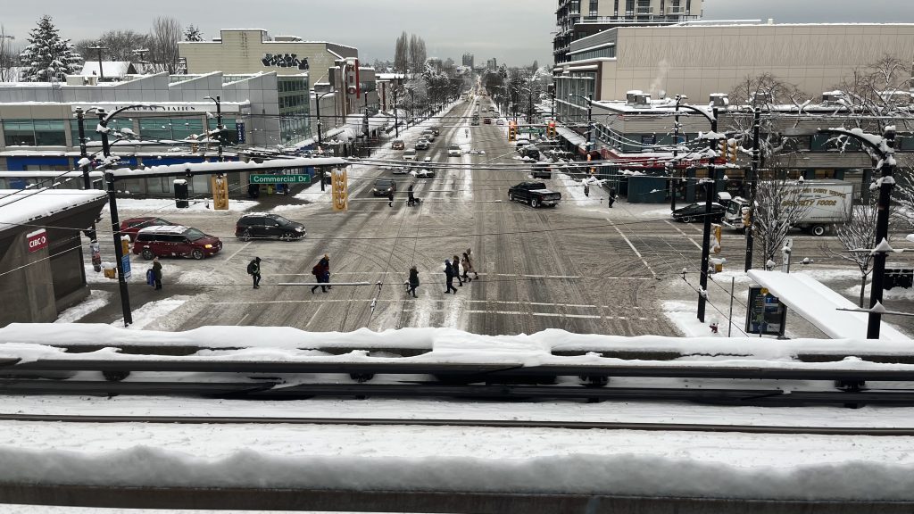 Intersection covered in snow with a Skytrain track in the foreground