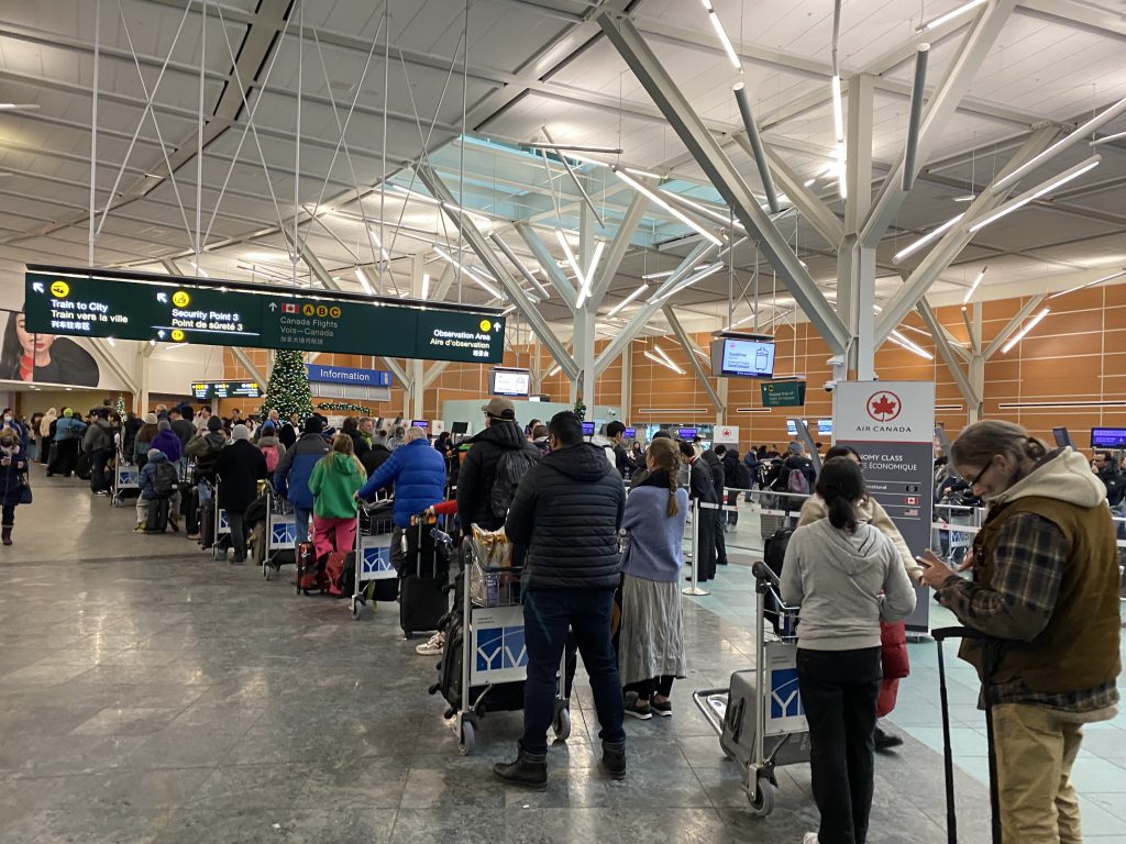 YVR passengers standing in the airport and experiencing cancelations and delays due to weather complications.