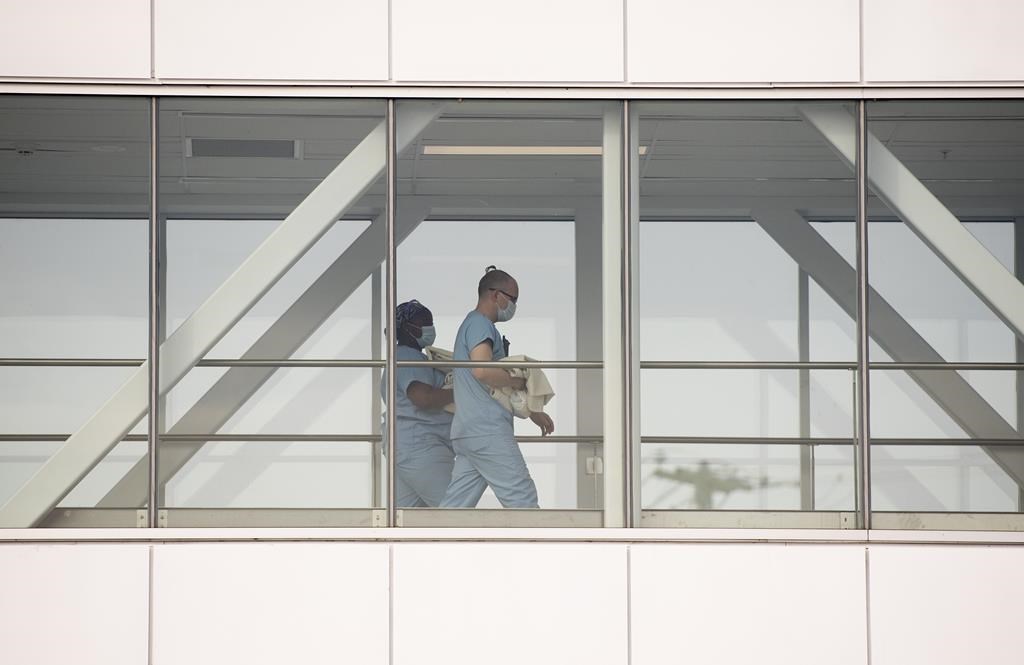 Health-care workers walk across a sky bridge at a hospital in Montreal, Sunday, Feb. 6, 2022.