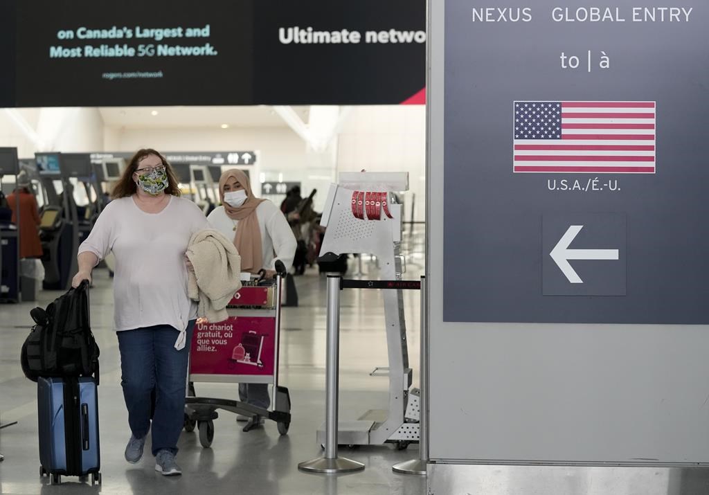 People travel to the United States of America at Pearson International Airport in Toronto, Friday, Dec. 3, 2021. THE CANADIAN PRESS/Nathan Denette