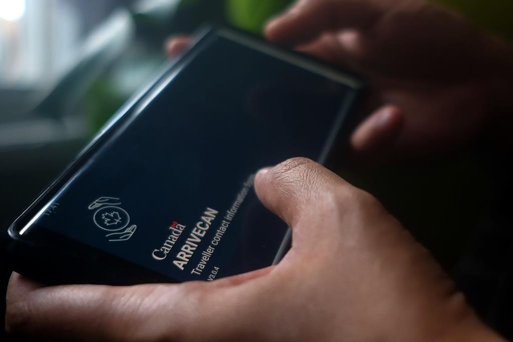 A person holds a smartphone set to the opening screen of the ArriveCan app