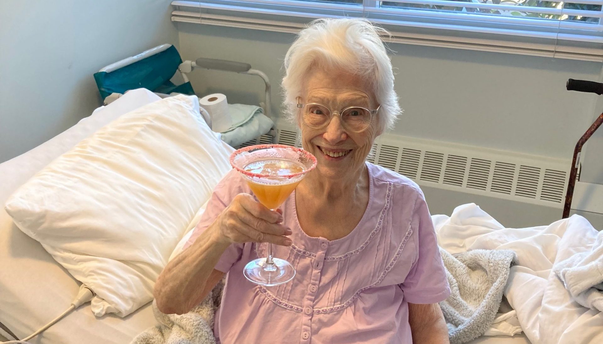 Donella Krebs poses for a photo with a drink in her hand in her room at the Lakeshore Care Centre in Port Coquitlam